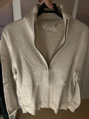 Full zip kofta - Säljer en stilren beige kofta från Dobber i storlek M. Koftan är full zip och i väldigt bra skick. Säljs för 299kr. Kontakta mig om du har frågor.