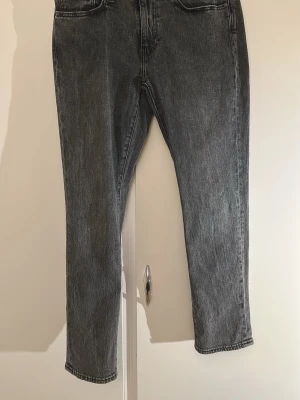 Levi's 511 gråa jeans W31 L30 - Säljer ett par Levi's Premium 511 jeans i svart tvättad denim. Modellen har en slim passform med klassiska fem fickor och raka ben. Jeansen har snygga detaljer som Levi's patch bak och den ikoniska röda etiketten vid bakfickan.