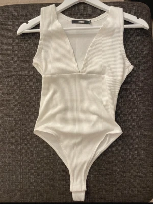 Vit ribbad body från Bik Bok - Säljer en body från Bik Bok i storlek S. Den har ribbad struktur, djup v-ringning och är ärmlös. Helt oanvänd!!! 