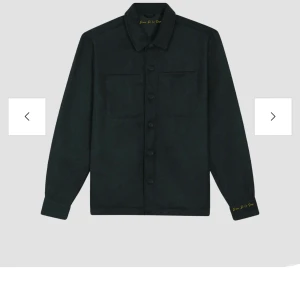 Svart overshirt från Donce De La Sense - Stilren svart overshirt från Donce De La Sense med klassisk krage, två bröstfickor och knäppning framtill. Jackan har lång ärm och diskret broderad logga i guld på ärmslutet. Tillverkad i mjukt ullmaterial som ger en clean och modern look. Hör av dig om du har några frågor ☺️