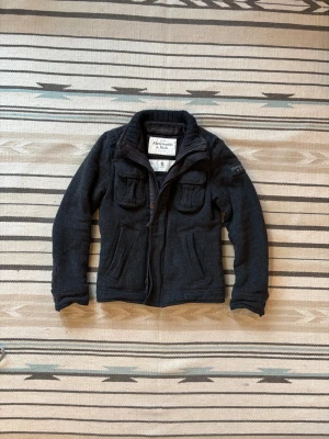 Grå jacka från Abercrombie and fitch - Riktigt snygg o varm jacka perfekt inför vinter/våren. Använd men utan defekter!