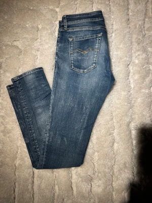 Replay jeans blå waist 27/30 - Snygga blå jeans från Replay, med klassisk femficksdesign och ljus och lite glänsasde tvätt. Jeansen har raka ben och dekorativa sömmar på bakfickorna. Tillverkade i slitstarkt denim med en bekväm passform som passar perfekt till din vardagsstil.