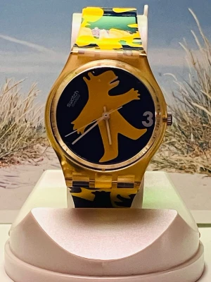 Cool Swatch klocka i Gul&Blå  - Säljer en cool Swatch klocka med ett unikt motiv på urtavlan och ett matchande armband i gul och blått. Klockan har ett quartz urverk.Rustad med nytt batteri, levereras i befintligt fungerande skick enligt bilderna!