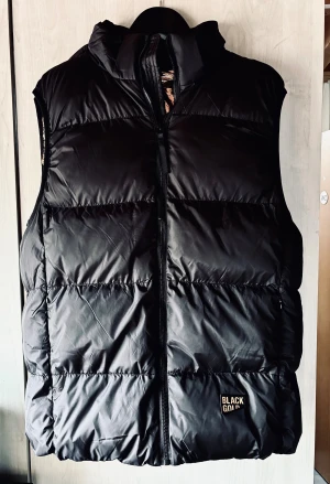 Svart pufferväst från Black Gold! - Svart pufferväst med fickor fram och avtagbar huva från Black Gold i storlek L. Ny och oanvänd.
