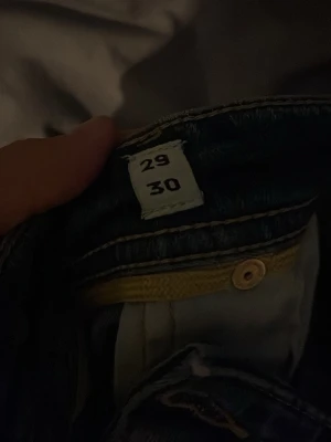 Jack and Jones Tapered Mike jeans mörkblå 29/30 - Snygga mörkblå jeans från Jack and Jones , modell Tapered Mike. Jeansen har klassisk femficksdesign, gul kontrastsöm och knappstängning. Passformen är tapered med smalare ben och de är tillverkade i slitstarkt denimtyg. Perfekt för dig som gillar stilrena och moderna jeans.