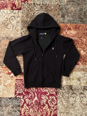 Svart polo Ralph lauren zip hoodie  - En ny svart polo Ralph lauren zip hoodie i storlek S. Tröjan är oanvänd men har tyvärr tappat pappers tagen som ramlat av under frakten. 