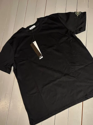 Svart Stone Island t-shirt. - Svart T-shirt från stone island med patch logo på sidan i storlek M. Aldrig använd. 