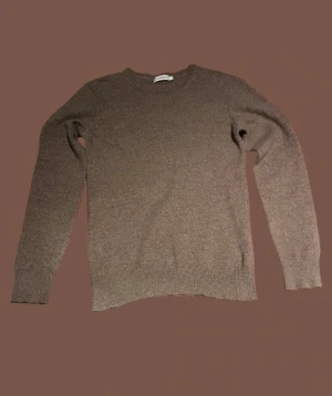 Beige kashmirtröja från J.Lindeberg - Snygg beige stickad tröja från J.Lindeberg i storlek M. Tillverkad i lyxig blandning av 70% superfin merinoull och 30% kashmir. Rund hals och ribbade muddar vid ärmslut och nederkant. Perfekt för dig som gillar stilrena och mjuka plagg. Säljer då den är för liten. Passar s då jag tror den krympt i tvätten. Finns en liten skada på armen, märks inte av.