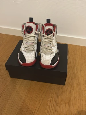 Nike Air Jordan 6 Retro vit/röd - Nike Air Jordan 6 Retro sneakers i vitt, svart och rött med högt skaft och klassisk Jumpman-logga på plösen. Skorna har snörning, platt sula och detaljer i skinn och syntet. Snygg kontrast mellan färgerna och ikonisk design för dig som gillar streetstyle.
