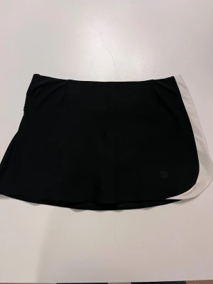 Wilson padelkjol tenniskjol XS svart med vit sida - Wilson padelkjol tenniskjol XS svart 