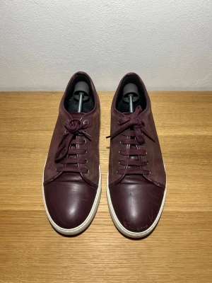 Lanvins - Säljer ett par Lanvins i vinrött i storlek 10 så sitter som 44. Mockan är som ny och bara några repor på toeboxen! Priset är ej hugget i sten så hör av er med prisförslag och frågor!