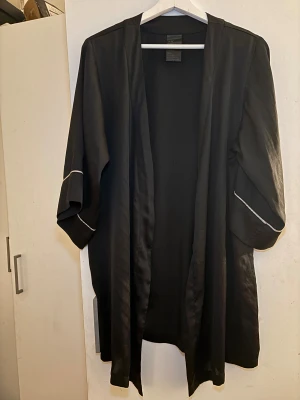Svart lång silk morgonrock från H&M - Svart lång silk robe från H&M , öppen front utan knäppning. Perfekt att slänga över en outfit för en chill och stilren look.