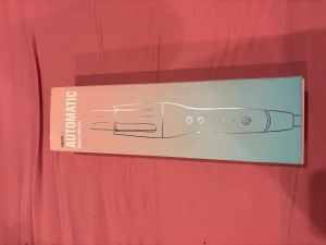 Novus automatisk hårlocktång - Säljer en Novus automatisk hårlocktång i svart med detaljer i silver och guld. Ergonomisk design med flera knappar för inställningar och digital display. Passar alla hårtyper och har anti-skald funktion samt snabb uppvärmning. Perfekt för att skapa snygga lockar snabbt.