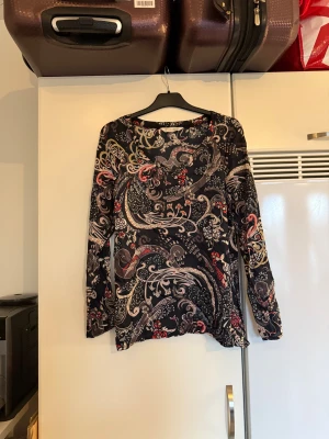 Odd molly blus  - Säljer en superfin blus med en svart bottenfärg med superfin detaljer i beige och rött, Från märket Odd Molly. Storlek 2 som enligt deras storleksguide motsvarar en M. Mycket fint skick, jag hittar inga synliga anmärkningar eller defekter. 