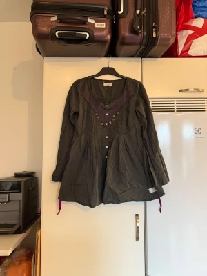 Odd molly tunika  - Säljer en superfin mörkgrön tunika med knappar ända ner o u lila broderi men volanger på bröstet. Från märket Odd Molly. Storlek 2 som enligt deras storleksguide motsvarar en M. Fint skick, men kan vara något blekare än ny, 