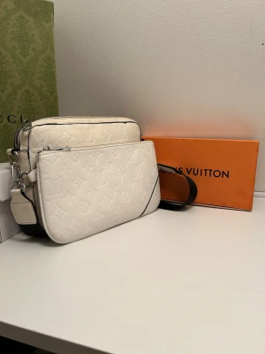 Väska Vit - Hjälper en vän att sälja denna väskan då den ej används längre. Väskan är bra skick förutom en liten grej som är lite lös på bandet och att den är lite skitig i färgen men inte så konstig med tanke på färgen. Annars är väskan superfin och passar jättebra till typ allt. Någon fråga eller så hör av er!  Skriv för bild på lösa grejen på bandet så löser jag det :) Mvh 