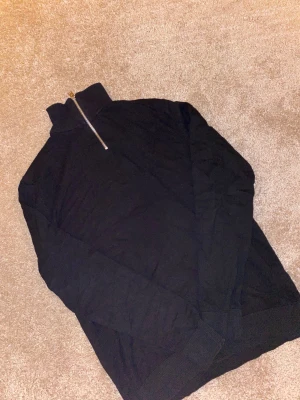 Svart stickad half zip från Jack & Jones - Svart stickad tröja från Jack & Jones med hög krage och snygg half zip-dragkedja. Perfekt för lager-på-lager och chill stil. Långärmad modell i mjukt material som håller dig varm under kyliga dagar.