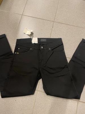 Svarta slim jeans Tiger of Sweden - Säljer ett par svarta slim fit jeans från Tiger of Sweden. Klassisk femficksmodell med snygg passform och diskret logga på bakfickan. Jeansen är tillverkade i ett mjukt bomullsmaterial med lite stretch för extra komfort.