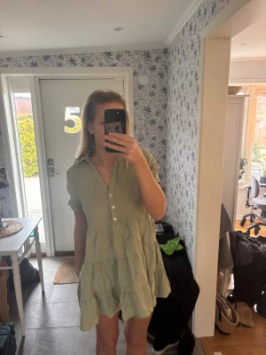 Ljusgrön kort klänning från Zara - Supersöt ljusgrön klänning från Zara i storlek S. Klänningen har kort ärm, krage och knappar framtill. Den är tillverkad i linne och har en volangig, avslappnad passform. Säljer pga att den blivit för kort, är 173 cm🩷
