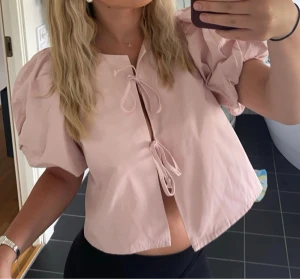 Ljusrosa blus med puffärmar och knyt - Supersöt ljusrosa blus med korta puffärmar och två knyt framtill från Gina tricot!