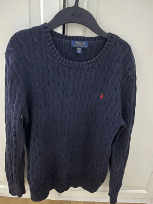 Polo Ralph Lauren mörkblå stickad - Polo Ralph lauren mörkblå stickad. Den är i storlek XL (kids), som motsvarar ungefär S i vuxenstorlek. Den är i fint skick och passar utmärkt om du är 170-180. Ny pris är ungefär 1500kr 