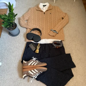 Beige stickad tröja Polo Ralph Lauren - Säljer en beige kabelstickad tröja från Polo Ralph Lauren med halv dragkedja och broderad marinblå logga på bröstet. Tröjan har långärmad design, ribbade muddar och är tillverkad i mjuk bomull. Perfekt för dig som gillar klassisk och chill stil.