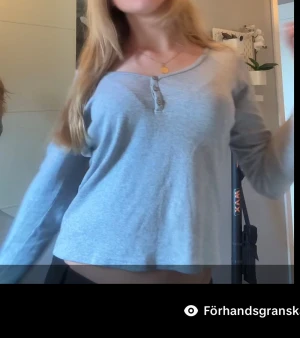 Ljusgrå långärmad tröja med knappar - Säljer en ljusgrå långärmad tröja med rund hals och tre dekorativa knappar framtill. Tröjan har en avslappnad passform och är perfekt för chill dagar. Mjuk och skön mot huden, passar dig som gillar enkel och stilren look.