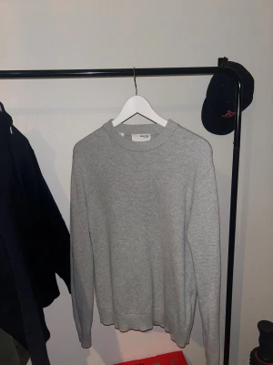 Ljusgrå stickad tröja från Selected Homme - Säljer en stilren ljusgrå stickad tröja från Selected Homme. Tröjan har rund halsringning, ribbade muddar och är långärmad. Använd 1 gång.