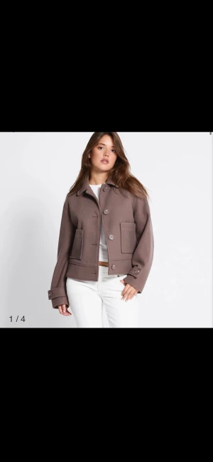 Brun kort rock med stora fickor - Säljer en brun kort rock med klassisk krage och stora framfickor. Jackan har knappar framtill och på ärmsluten, samt en loose passform som ger en chill vibe. Perfekt för dig som gillar stilrena och enkla plagg med lite edge.