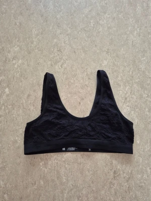 Sport- behå - Svart sport-bh från Cubus med breda axelband och snygg spetsdetalj över hela framsidan. Sport-bh är stretchig och har en ribbad kant nedtill för extra komfort. Perfekt att styla under en skjorta eller som den är till jeans.