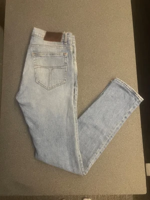 Ljusblå jeans Tiger of Sweden Evolve 30/32 - Snygga ljusblå jeans från Tiger of Sweden, modell Evolve, med klassisk femficksdesign och bruna sömmar. Skygga nyanser. Jeansen har en rak passform och är tillverkade i mjukt denim-material. Perfekt för dig som gillar en clean och avslappnad stil.  Pris kan diskuteras!!