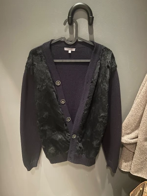 Svart kofta med päls från Nikolaj - Nu finns den här feta tröjan ute som är från Nikolaj och väldigt sällsynt. Tröjan har svart färg men de ser ute att vara lila på bildern. Det som gör tröjan väldigt sällsynt är dess päls. Tröjan är perfekt nu inför vinter då den är väldigt varm. Tröjan är 100 % äkta, hör av er vid funderingar och kan såklart gå ned i pris!