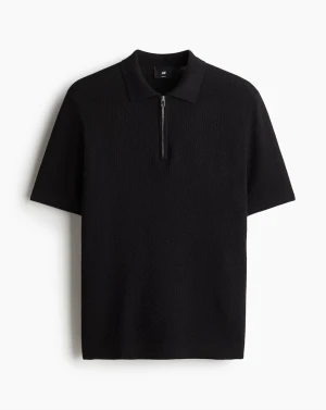 Mörk pikétröja med half zip från H&M - Svart pikétröja från H&M med snyggt strukturerat mönster och krage. Tröjan har en silverfärgad half zip-dragkedja framtill och korta ärmar. Materialet är mjukt och känns skönt mot huden, perfekt för dig som gillar stilrena och moderna plagg.