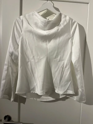 Vit silkeströja med snörning Gina Tricot - Säljer en vit långärmad silkeströja från Gina Tricot i blankt, mjukt material. Toppen har snygg drapering och öppen rygg med snörningsdetalj upptill. Perfekt för dig som gillar stilrena och trendiga plagg med det lilla extra. Tröjan är använd fåtal gånger