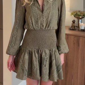  kort klänning med spetsdetaljer - Supersnygg grön kort klänning med långärmade ärmar och v-ringning med knappar framtill. Klänningen är från Feeling friday som är en norsk sida. Klänningen är helt ny, med lappen kvar, säljer på grund utav storleken som blev fel. Orginalpris ligger på 1235kr + 400kr tullavgift då Norge inte är med i EU. Säljer dock utan tullavgift summan. 