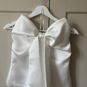 Vit satintopp från zara - Supersöt vit topp från Zara i satin med en stor rosett framtill. Perfekt för dig som vill sticka ut med en statement piece och älskar detaljer. Fin till fest