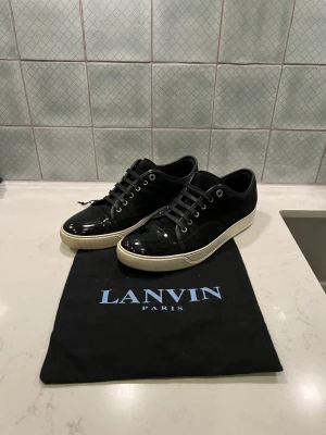 Svarta Lanvin skor - Säljer ett par svarta Lanvin skor med snygg kontrast mellan mocka och lackad tå. Skorna är i mycket fint skick och sparsamt använda. Storleken är UK9 (43-44) dustbag ingår. Hör av dig vid frågor! 