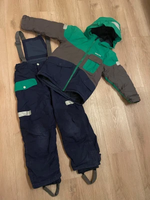 Skiddress set jacka + byxa - Didriksson skidset täckjacka och täckbyxor mörkblå med gröna detaljer storlek 120. Upplevs ngt stor i storleken. I använt skick.