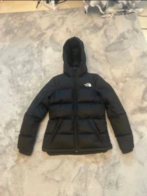 Svart pufferjacka från The North Face - Säljer en svart pufferjacka från The North Face i storlek S. Den är tjockt vadderad och är perfekt för kalla dagar! Köpte på Vinted men säljer vidare då den inte passade mig! Den har en färgfläck på ena armen men det är inget som stör helhetsintrycket😊🩷