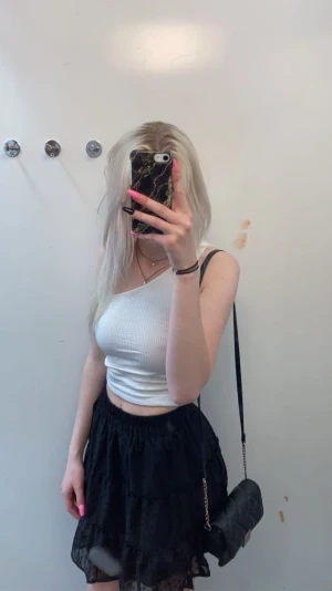 Svart volangkjol  - Supersöt svart kortkjol med volanger och diskret prickigt mönster. Perfekt att styla med crop tops eller stickade tröjor.