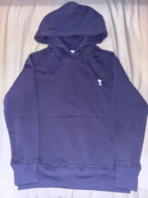 Ami Paris hoodie - Säljer en snygg blå hoodie från Ami Paris med det klassiska broderaderiet. Perfekt för dig som gillar stilrena och coola plagg med en twist.