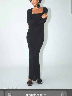 Svart glittrig långklänning Gina Tricot - Supersnygg svart långklänning från Gina Tricot med glittrigt tyg och fyrkantig ringning. Klänningen har lång ärm och figurnära passform som framhäver siluetten. Perfekt för dig som vill sticka ut med stilren elegans.