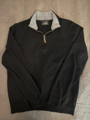 Svart half zip tröja Nordstrom - Svart långärmad tröja från Nordstrom Men's Shop i 100% merinoull. Tröjan har en grå ribbad krage och half zip-dragkedja framtill. Perfekt för dig som gillar stilrena och bekväma plagg med lite sportig touch.