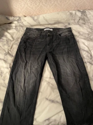 Svarta jeans från Bershka, storlek 42 - Svarta jeans från Bershka i klassisk femficksmodell. Jeansen har rak passform och är tillverkade i jeansmaterial med lätt tvättad look. Perfekt för dig som gillar enkel och stilren design. Storlek EUR 42, USA 32.