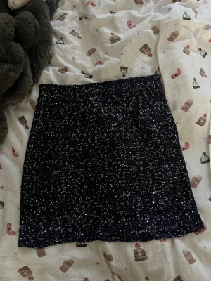 Marinblå glittrig minikjol - Säljer en marinblå glittrig kortkjol som är täckt med små paljetter för extra bling. Perfekt till nyår!