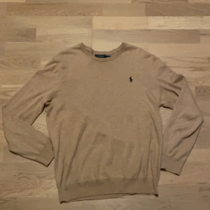 Beige slim stickad tröja Polo Ralph Lauren - Snygg beige stickad tröja från Polo Ralph Lauren i slim fit. Tillverkad i mjuk bomull. Plagget har inga defekter.