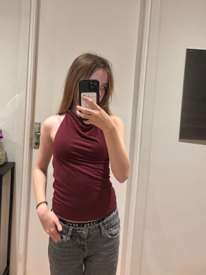 Vinröd halterneck linnetopp Gina Tricot - Säljer en vinröd halterneck linnetopp från Gina Tricot i storlek XS. Toppen är ärmlös och har en snygg tight passform med hög hals. Materialet är mjukt och stretchigt, troligen bomull eller syntet. Perfekt att styla med jeans eller kjol för en nice look 