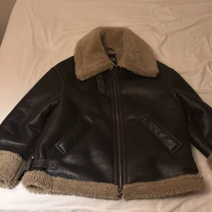 Brun teddyjacka från Zara, storlek S - Säljer en brun teddyjacka från Zara i storlek S med mjukt beige foder och krage. Jackan har dragkedja framtill, två snedställda fickor och detaljer i skinnimitation. Perfekt för kalla dagar med sin fluffiga look och breda krage.