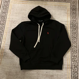 Polo Ralph lauren hoodie - Säljer nu en helt ny polo Ralph lauren hoodie i svart med röd detalj i storlek M den är i mycket fint skick och nästan aldrig använd inga defekter finns eller hål fråga om nu undrar något passar 180 ungefär💸🫡🔥🙌