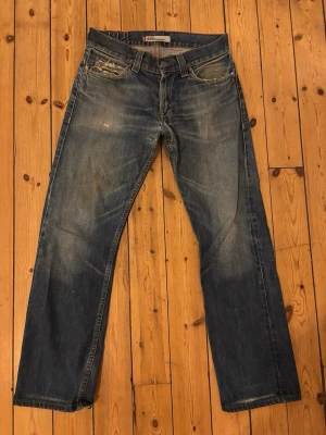 Vintage Levi's 506 boot cut  - Säljer ett par Levi's 506 jeans i klassisk blå tvätt med slitna detaljer och snygga slitningar vid fickorna. Jeansen har rak passform och är tillverkade i robust denim. Perfekt för dig som gillar en avslappnad och autentisk jeanslook.